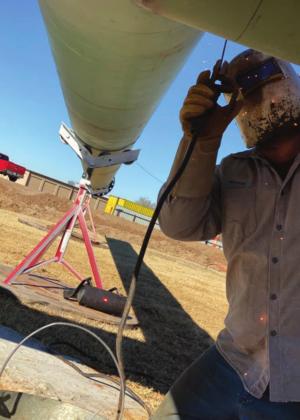 Blayne Barnes works on welding parts of a 60-foot cross together. The cross is being erected at the Watonga Church of the Nazerene. Photo Provided Watonga Republican
