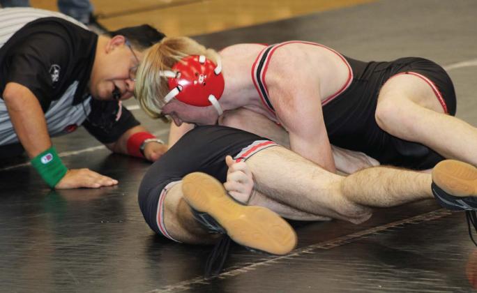 At top: A Bison athlete strong arms a Watonga wrestler. The ref is on the floor with the athletes to keep up with scoring. .Below, at right, Elliot Harrall takes hold of her opponent.