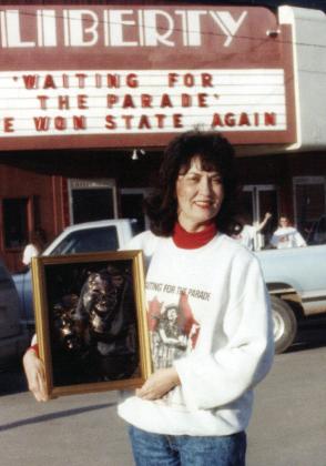 Patt Ward Curtin in front of the Liberty Theatre marquee with the state winning plaque from the play she directed, Waiting for the Parade. This show went on to place fourth at the National Competition held in Knoxville, Tenn. The crew transported their set in a stock trailer.