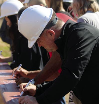 Watonga Superintendent of Schools Kyle Hilterbran signs the last support beam for the new gym. The construction bids were let in January.