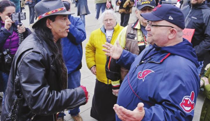 In this April 10, 2015, file photo, Philip Yenyo, left, executive director of the American Indians Movement for Ohio, talks with a Cleveland Indians fan before a baseball game against the Detroit Tigers, in Cleveland. Now that the NFL's Washington Redskins have retired their contentious nickname and logo after decades of objection and a recent uproar from nationwide social protests, the Indians appear to be the next major sports franchise in line to change their identity. Mark Duncan I AP Photo