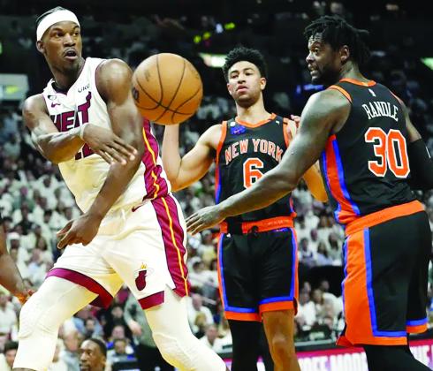 Miami Heat forward Jimmy Butler, left, passes the ball as New York Knicks Quentin Grimes (6) and Julius Randle (30) look on during the second half of Game 4 of the NBA basketball Eastern Conference playoff semifinal, Monday, May 8, 2023, in Miami. (AP Photo/Lynne Sladky)