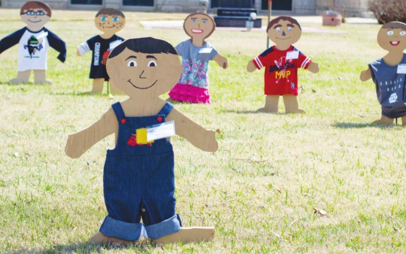 Wooden figures line up along the front lawn of the courthouse this month to help bring awareness to Child Abuse Awareness Month.