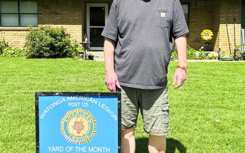 Johnny Fowler shows off his Yard of the Month sign presented for his neighborhood by the Watonga American Legion.