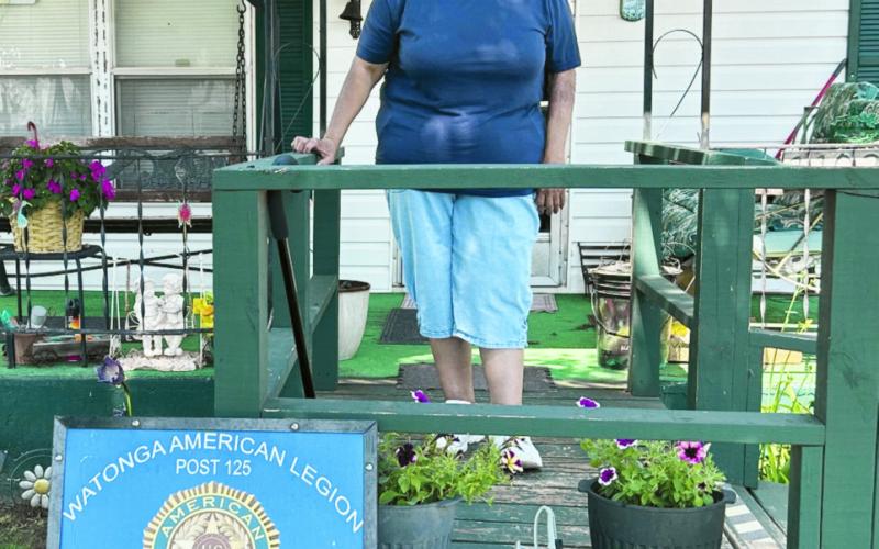 Normaleen Pyatt shows off her Yard of the Month sign presented for her neighborhood by the Watonga American Legion.