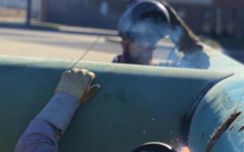Welders from Barnes Welding work on welding the beams of the cross together.