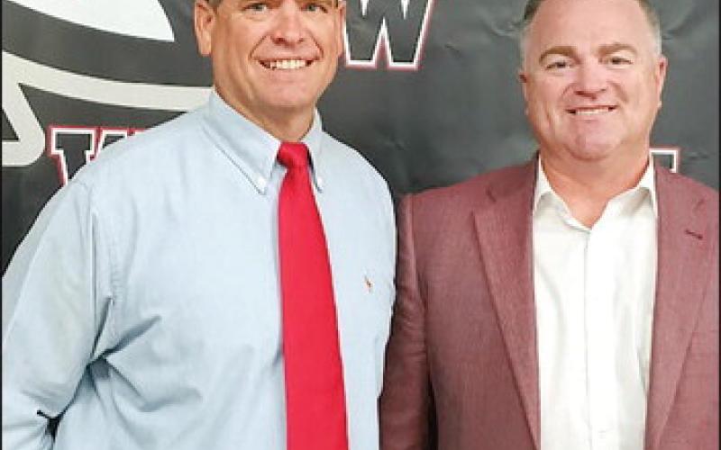 At Clint Benway and Superintendent Kyle Hitlerbran are all smiles in front of the Watonga Eagle in the board room. Benway has been named head football coach for the upcoming school year. Photo by Connie Burcham