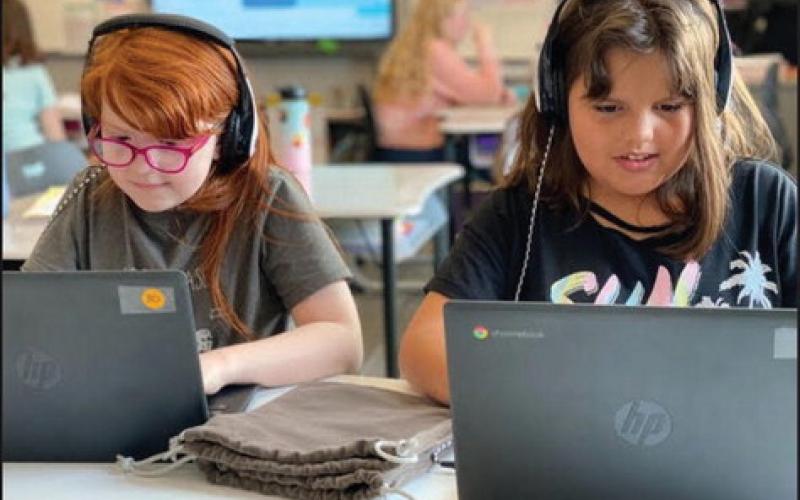 Fifth-grade students Lillie Colbert and Kennedy Fletcher wear new headphones bought with a CLASS Grant awarded to teacher Amanda Bowser at Rosewood Elementary in Broken Arrow Public Schools. CLASS Grants is a state Department of Education initiative using federal coronavirus relief funds. (Photo provided by the state Department of Education.)