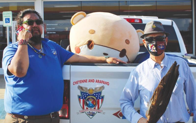 Alan Fletcher (left) and Larry Roman Nose pose with Bearsun at the Domino convenience store in Watonga on Monday, Sept. 6. Bearsun is walking across the country to raise money for charity.