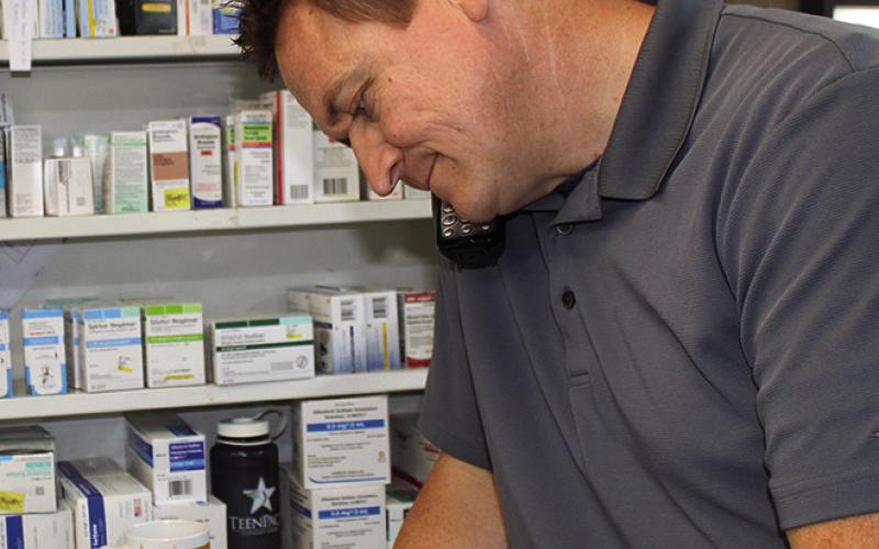 Pharmacist Zac Brack takes notes on a prescription from a prescriber on the phone. After 20 years as a pharmacist, Brack is purchasing City Pharmacy and Swann Pharmacy. The family will run the businesses from a single store front.