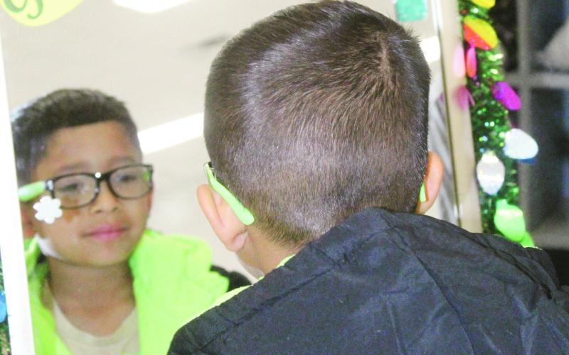 A Watonga Elementary School student admires himself in the mirror after selecting a coat with the help of a ‘personal shopper’ during the school’s Operation Warm, where every child recieved a coat. PHOTO by Connie Burcham