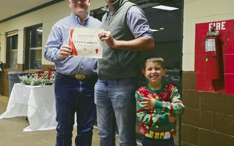 (L to R) Watonga Fire Chief Robert Daugherty presents Levi Garrett with a certificate naming him Watonga Volunteer Firefighter of the Year 2024. Garrett’s son, Jameson, is all grins over the event.
