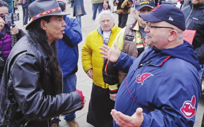 In this April 10, 2015, file photo, Philip Yenyo, left, executive director of the American Indians Movement for Ohio, talks with a Cleveland Indians fan before a baseball game against the Detroit Tigers, in Cleveland. Now that the NFL's Washington Redskins have retired their contentious nickname and logo after decades of objection and a recent uproar from nationwide social protests, the Indians appear to be the next major sports franchise in line to change their identity. Mark Duncan I AP Photo