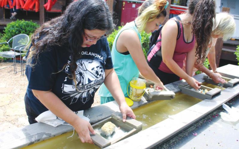 (Above) Sonora WhiteHorse, Sunny Toehay, Cynthia Skinner and Karan Brunken work the sluice box panning for gems at Roman Nose General Store. The gem panning is a newly added activity. Connie Burcham | Watonga Republican