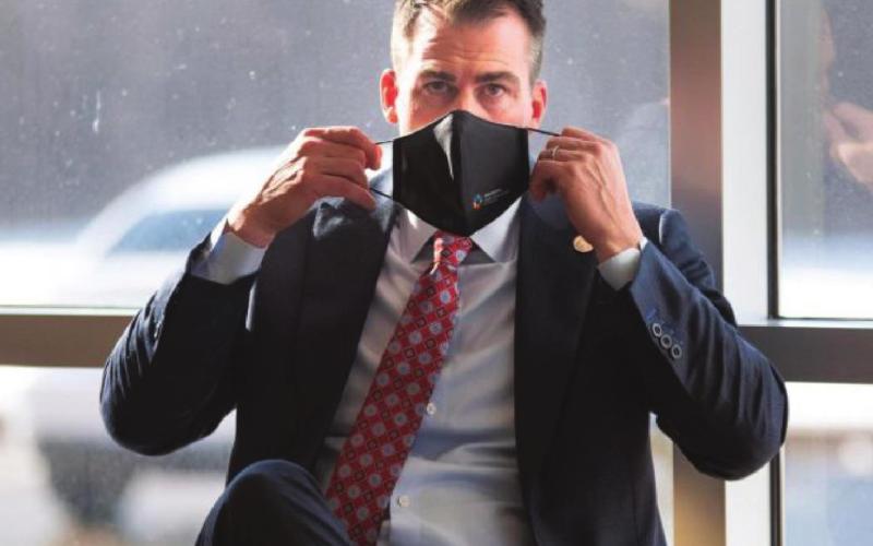 Gov. Kevin Stitt is seen putting on a mask after speaking to reporters at Integris Baptist Medical Center in Oklahoma City on Dec. 14, 2020. Whitney Bryen/Oklahoma Watch Watonga Republican