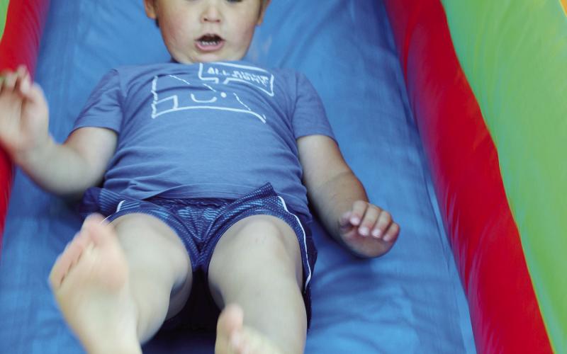 This youngster seems concerned he is going to take a different type of flight as he careens down the slide at the bounce house during the Watonga Fly-in Photo by Connie Burcham