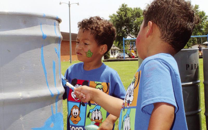 These twins are having an awesome time helping out the city by sprucing up the trash barrels for the city parks. The painting was part of the kids’ carnival at the Watonga Public Library. Photo by Connie Burcham