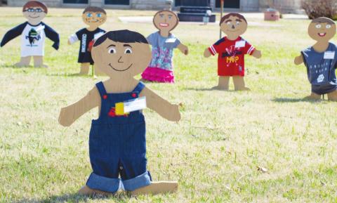 Wooden figures line up along the front lawn of the courthouse this month to help bring awareness to Child Abuse Awareness Month.