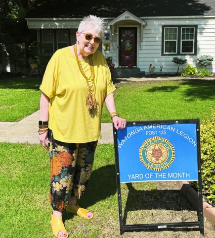 Patt Curtin shows off her Yard of the Month sign presented for her neighborhood by the Watonga American Legion.