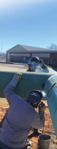 Welders from Barnes Welding work on welding the beams of the cross together.