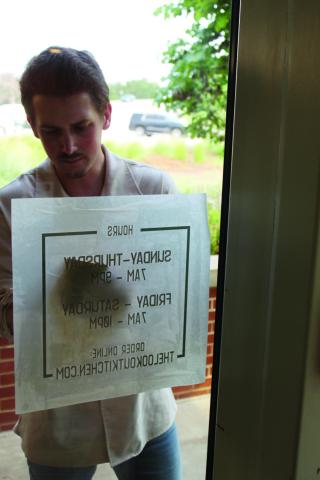 An employee applying signage when the Lookout Kitchen opened at Roman Nose State Park