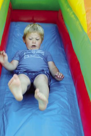 This youngster seems concerned he is going to take a different type of flight as he careens down the slide at the bounce house during the Watonga Fly-in Photo by Connie Burcham