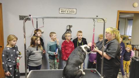 Darci Cash, owner of Furocious Beast pet groomer, demonstrates how to trim nails on a dog to Watonga 4-H members. Kinze Cowan, Keela Cowan, Brant Cowan, Kase Hilterbran, Sage Scheihing, Averie Morris, Wyatt Manke and Grady Scheihing look on.
